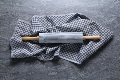 Photo of Rolling pin and kitchen towel on grey textured table, top view