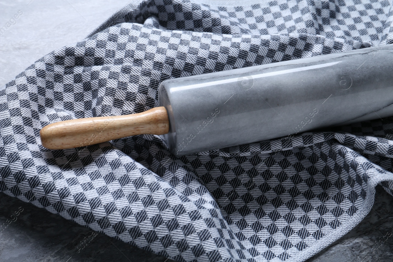 Photo of Rolling pin and kitchen towel on grey table, closeup