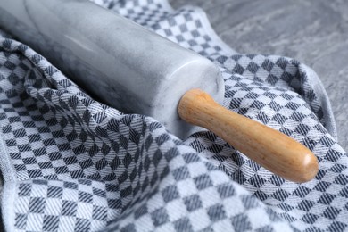 Photo of Rolling pin and kitchen towel on grey table, closeup