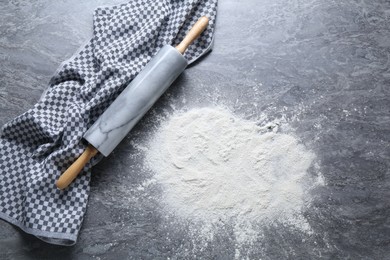 Photo of Rolling pin and flour on grey textured table, top view