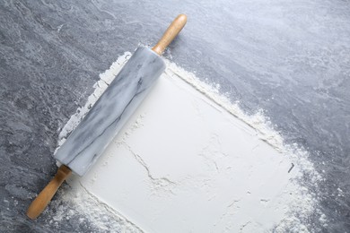 Photo of Rolling pin and flour on grey textured table, top view