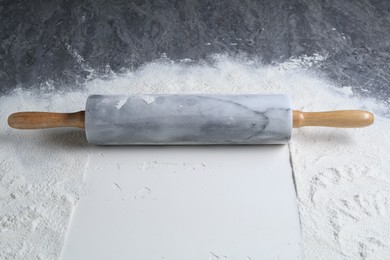 Photo of Rolling pin and flour on grey textured table