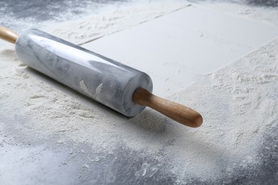 Photo of Rolling pin and flour on grey table, closeup