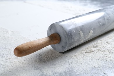 Photo of Rolling pin and flour on table, closeup