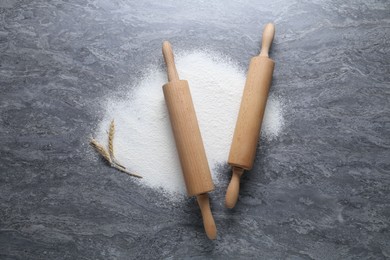 Photo of Rolling pins, flour and spikes on grey textured table, flat lay