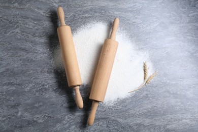 Photo of Rolling pins, flour and spikes on grey textured table, flat lay