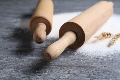 Photo of Rolling pins, flour and spikes on grey textured table, closeup