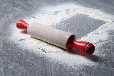 Photo of Rolling pin and flour on grey textured table, closeup