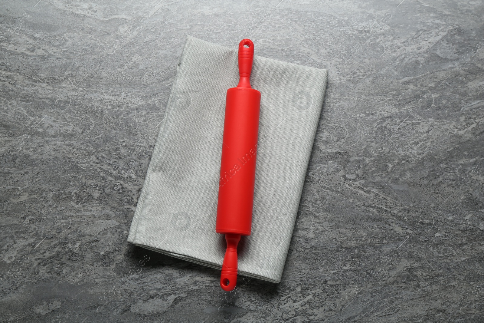 Photo of Red rolling pin on grey textured table, top view