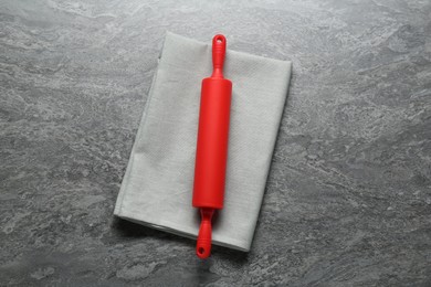 Photo of Red rolling pin on grey textured table, top view