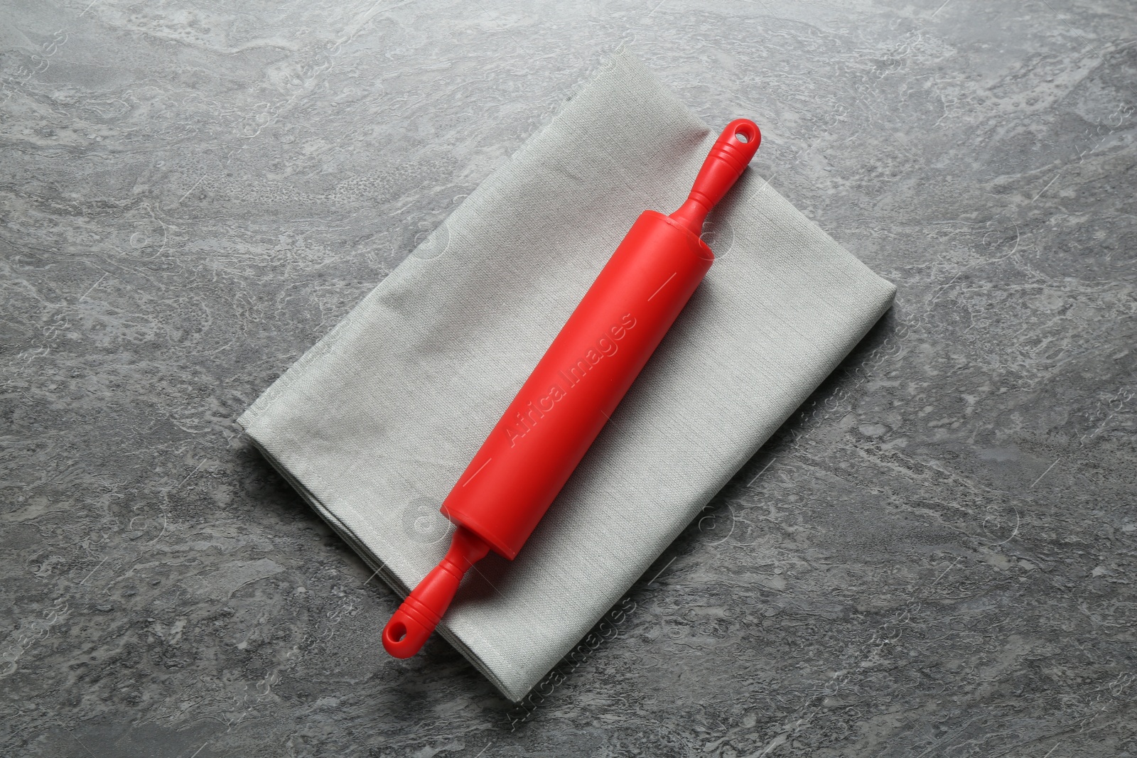 Photo of Red rolling pin on grey textured table, top view