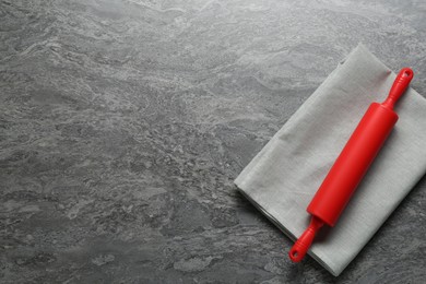 Photo of Red rolling pin on grey textured table, top view. Space for text