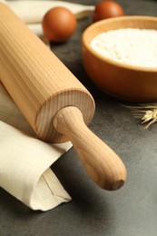 Photo of Rolling pin, bowl of flour, eggs and spike on grey table, closeup