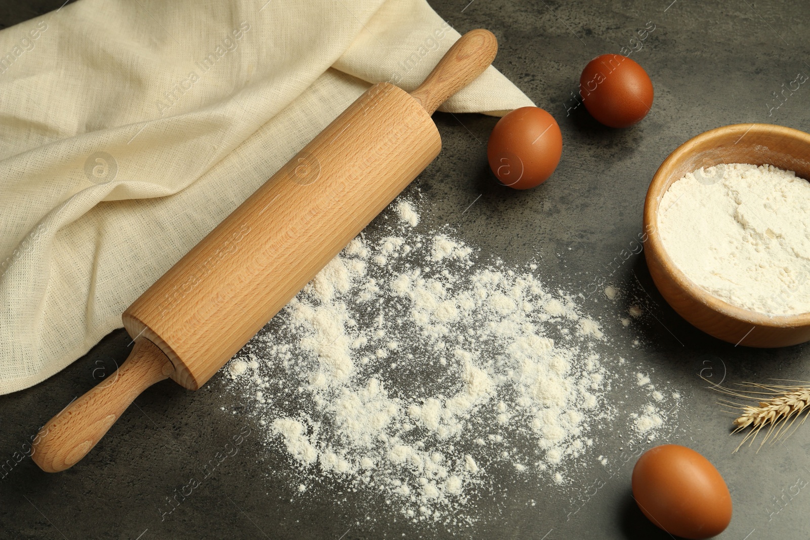 Photo of Rolling pin, bowl of flour, eggs and spike on grey table, above view