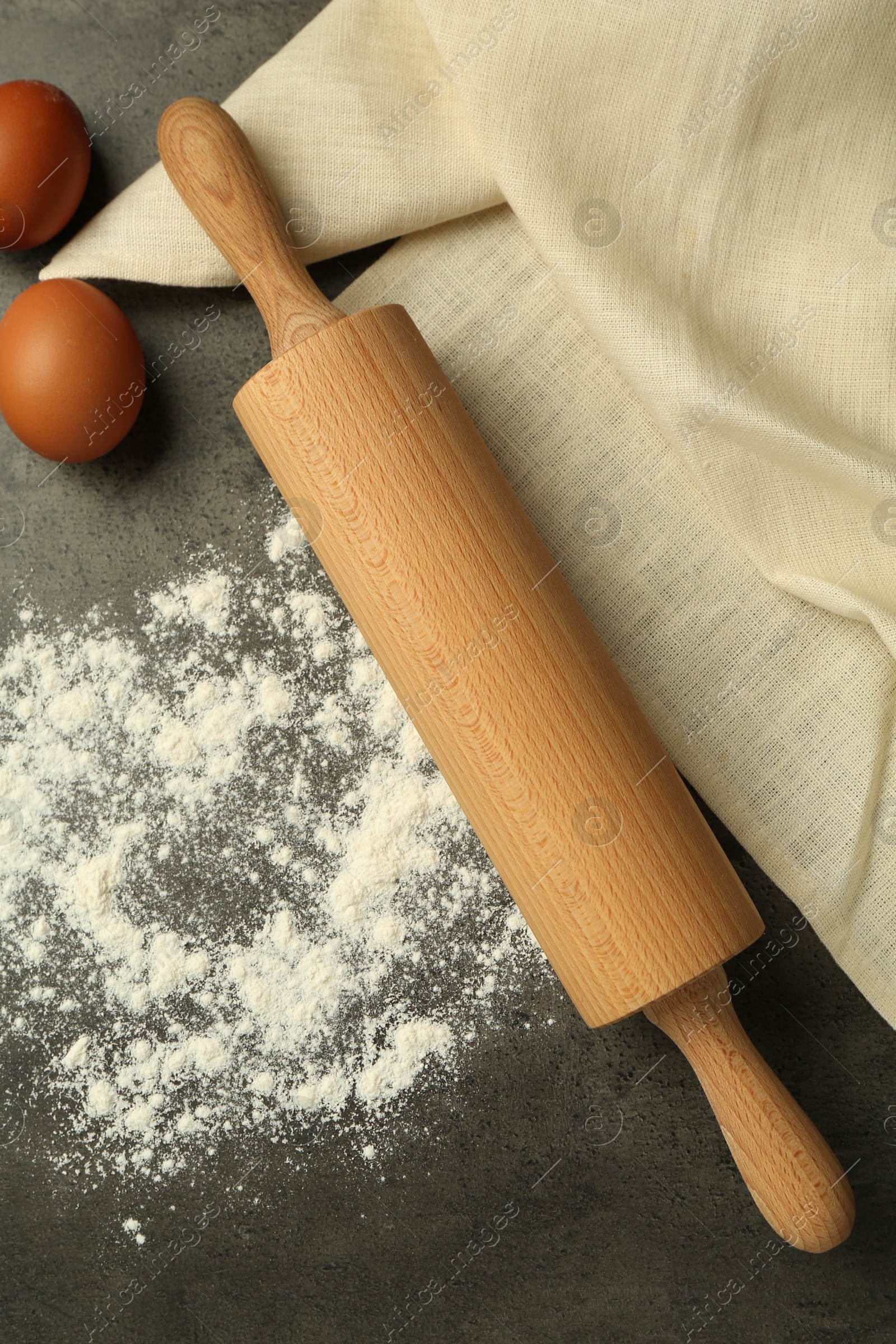 Photo of Rolling pin, flour and eggs on grey table, flat lay