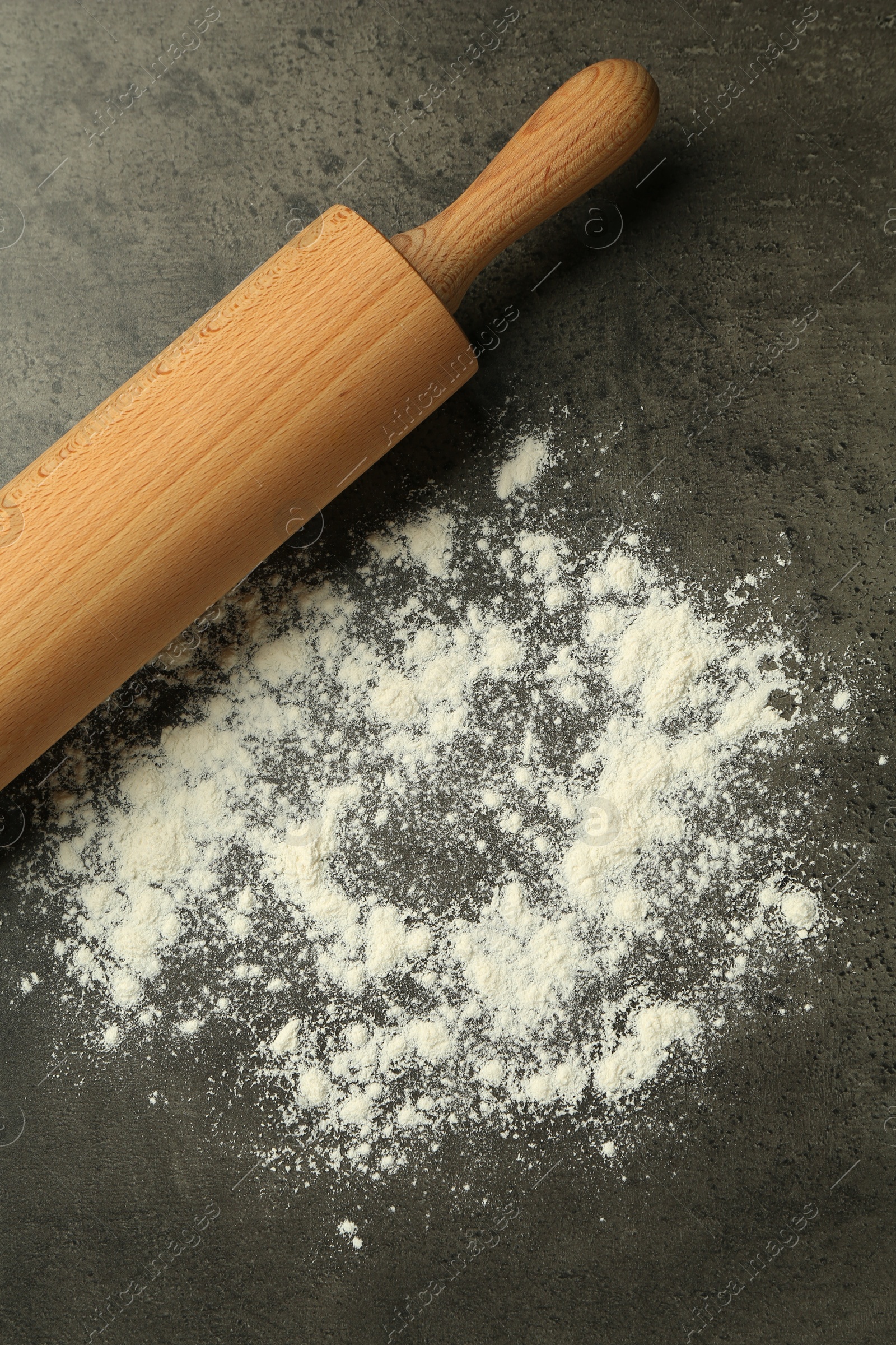 Photo of Wooden rolling pin and flour on grey table, top view