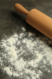 Photo of Wooden rolling pin and flour on grey table, closeup