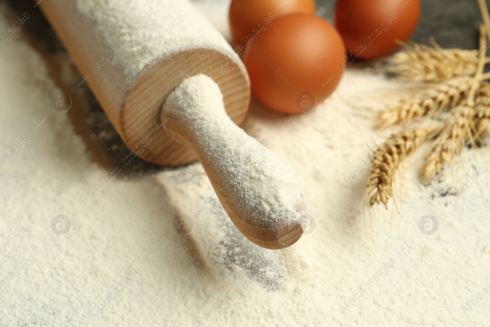 Photo of Wooden rolling pin, eggs, flour and spikes on table, closeup