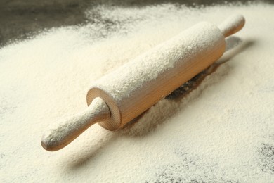 Photo of Wooden rolling pin and flour on table, closeup