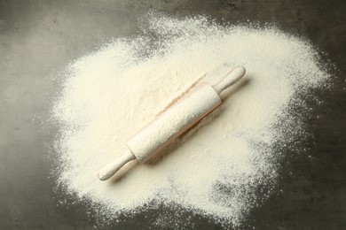 Photo of Wooden rolling pin and flour on grey table, top view