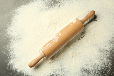 Photo of Wooden rolling pin and flour on grey table, top view