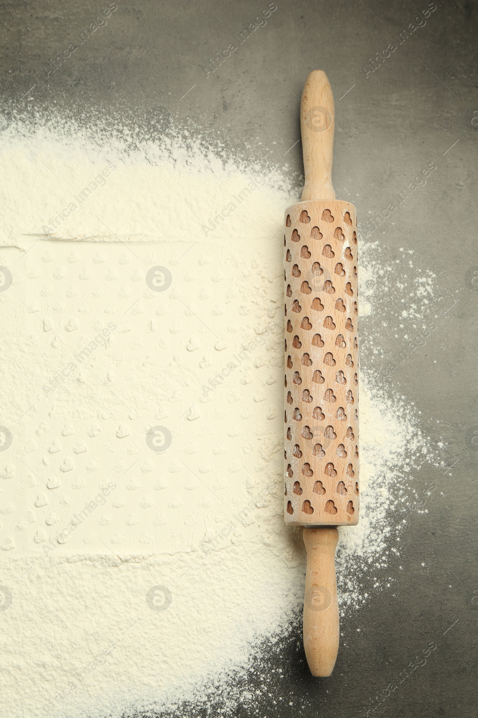 Photo of Wooden rolling pin and flour on grey table, top view