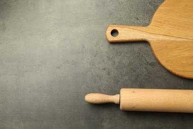 Photo of Wooden rolling pin and board on grey table, flat lay. Space for text