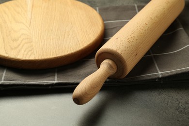 Photo of Wooden rolling pin and board on grey table, closeup