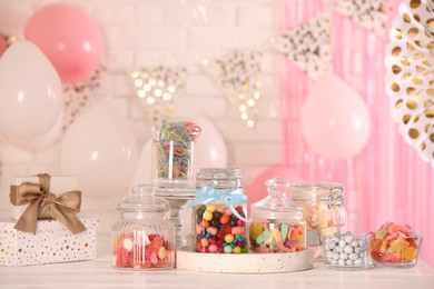 Photo of Candy bar. Many different sweets and gift boxes on white wooden table in festive decorated room