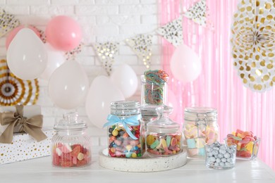 Photo of Candy bar. Many different sweets on white wooden table in festive decorated room