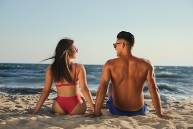 Photo of Lovely couple spending time together on beach, back view