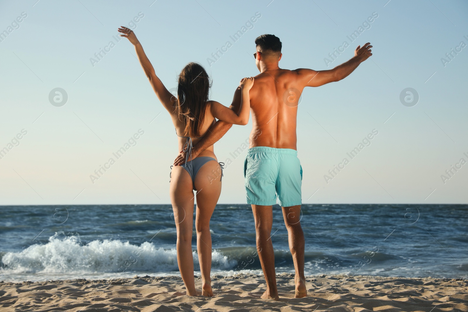 Photo of Lovely couple spending time together on beach, back view