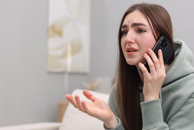 Photo of Depressed woman calling hotline for mental health help on sofa at home. Space for text