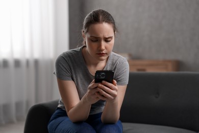 Photo of Depressed woman calling hotline for mental health help on sofa at home