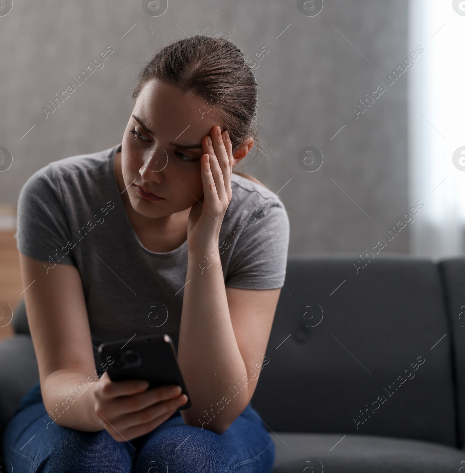 Photo of Depressed woman calling hotline for mental health help on sofa at home