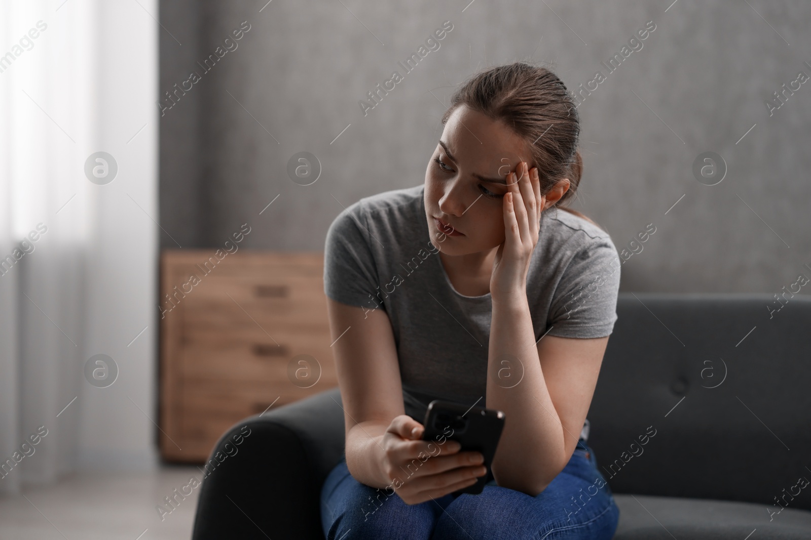 Photo of Depressed woman calling hotline for mental health help on sofa at home