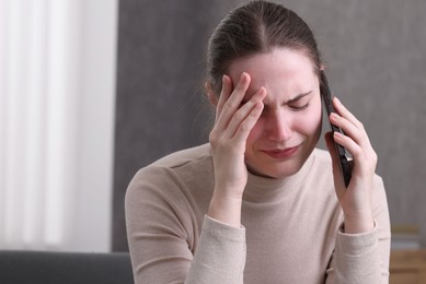 Photo of Stressed woman calling hotline for mental health help at home