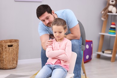 Photo of Resentful little girl and her father at home. Family dispute