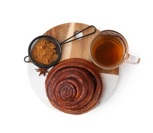 Photo of Delicious cinnamon roll bun, tea and spices isolated on white, top view