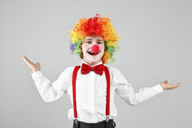 Photo of Happy little boy in clown wig and red nose on grey background. Surprise party