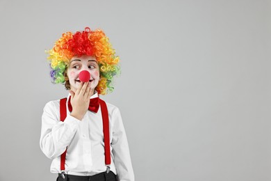 Photo of Cute little boy in clown wig and red nose on grey background, space for text. Surprise party