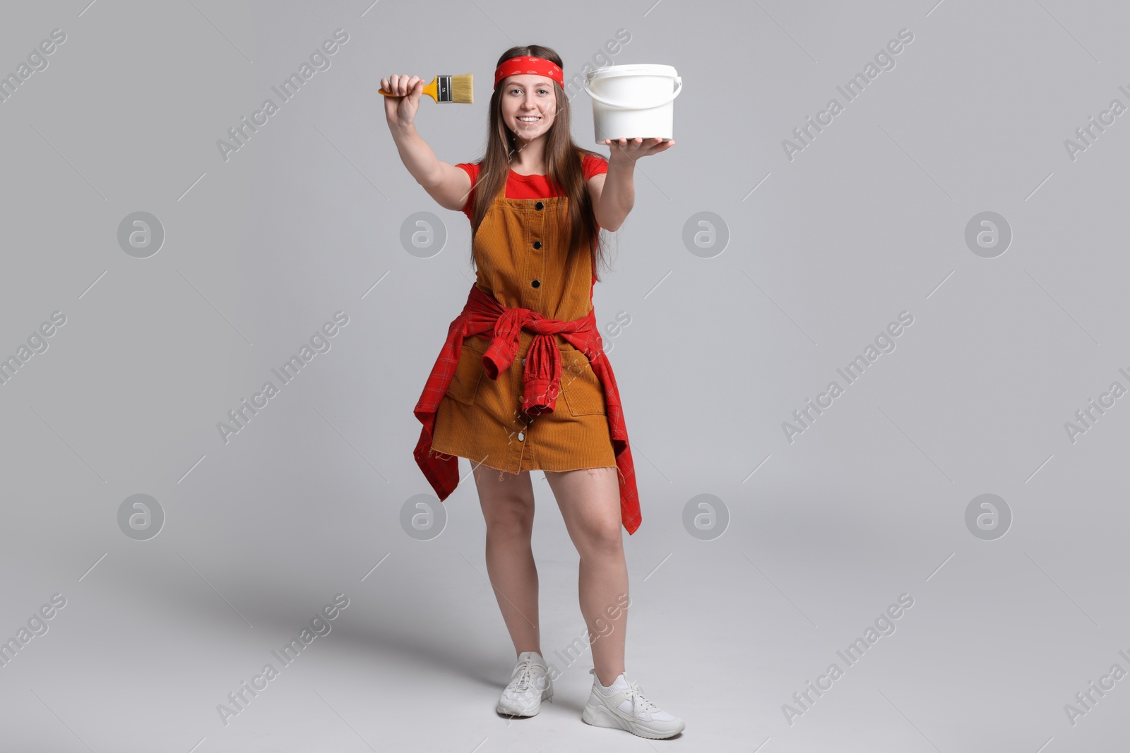 Photo of Woman with brush and bucket of paint on light grey background