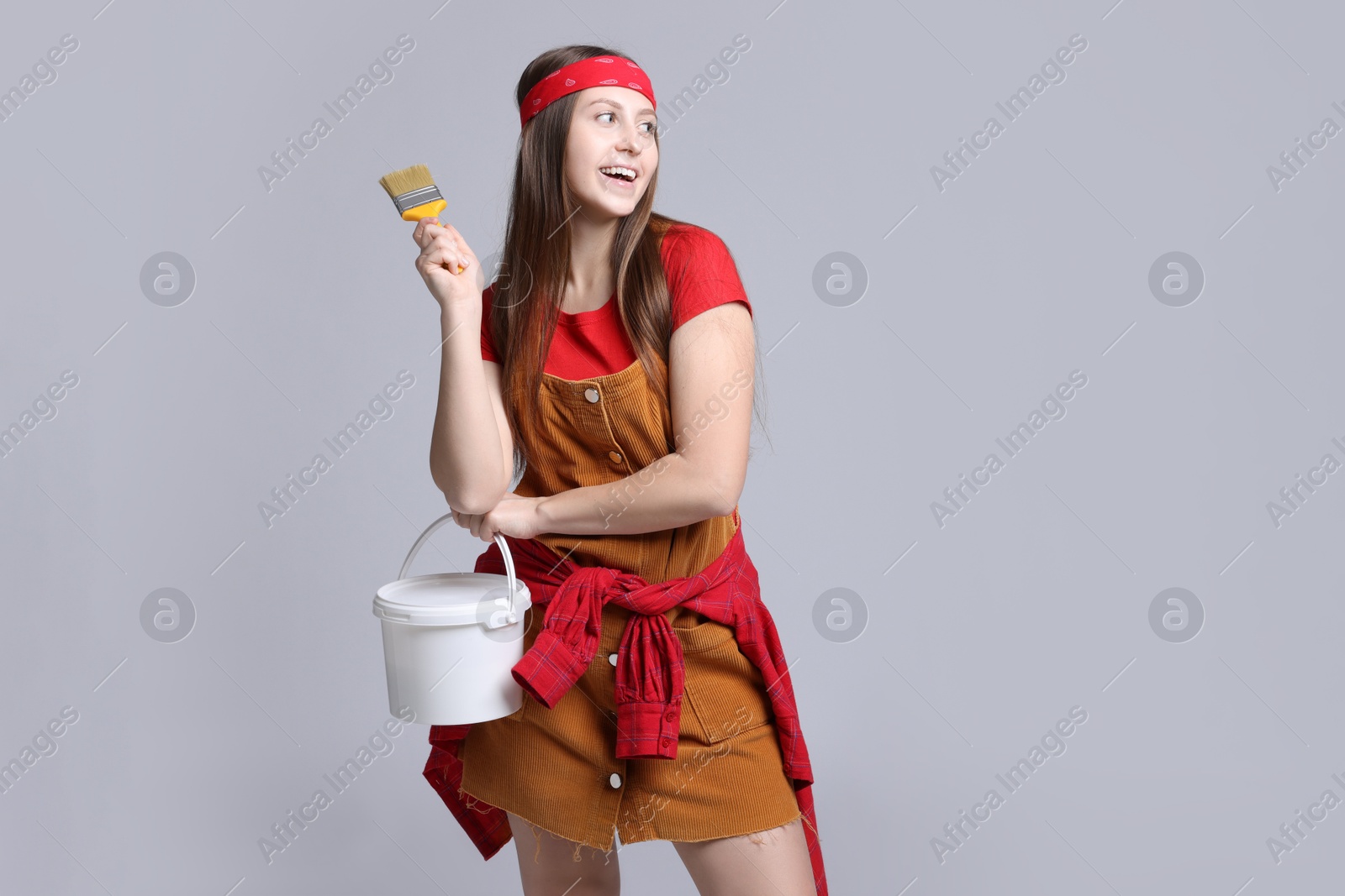 Photo of Woman with brush and bucket of paint on light grey background