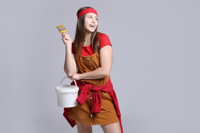 Photo of Woman with brush and bucket of paint on light grey background