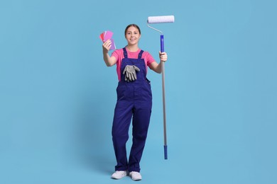 Photo of Professional painter with roller and color samples on light blue background