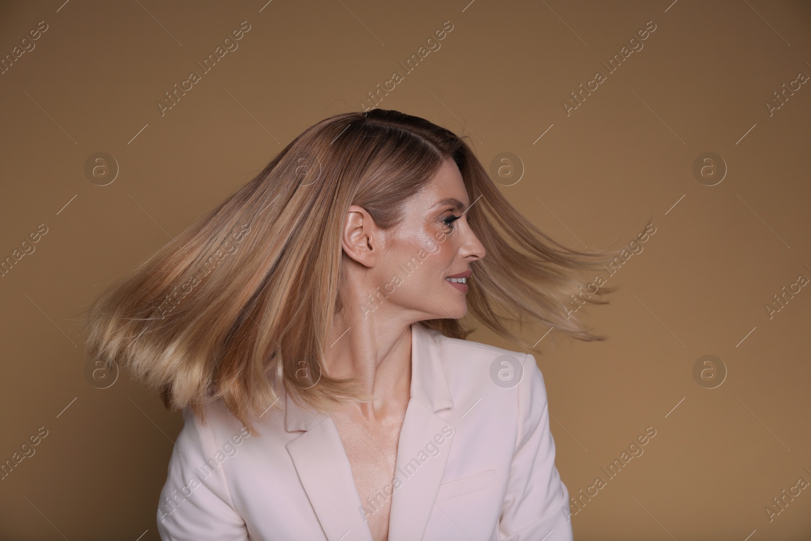 Photo of Beautiful woman with straight blonde hair on light brown background