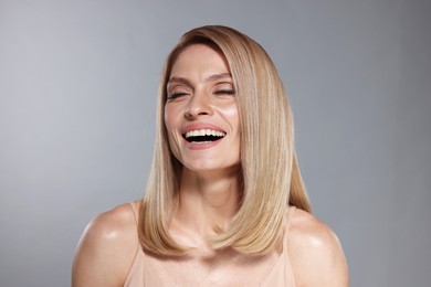 Photo of Portrait of beautiful happy woman with straight blonde hair on grey background