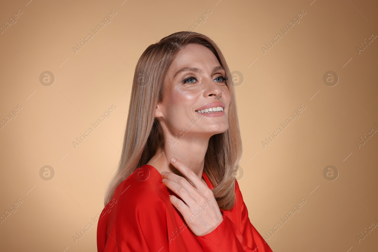 Photo of Portrait of beautiful happy woman with straight blonde hair on beige background