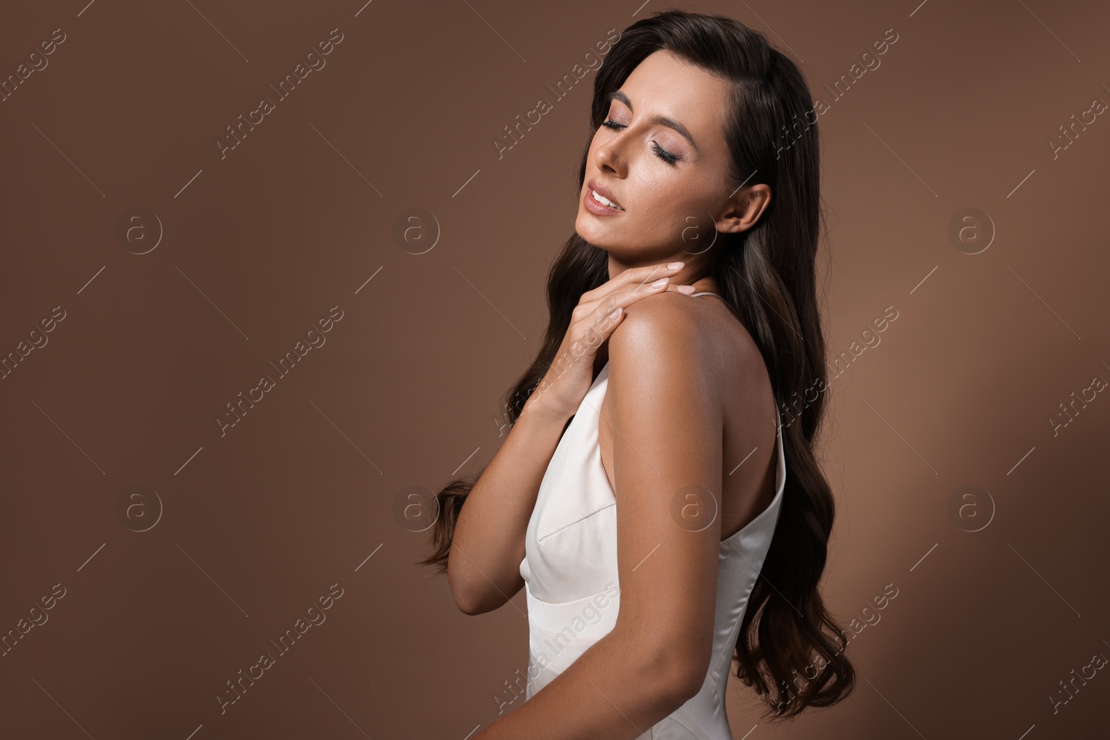 Photo of Hair styling. Beautiful woman with wavy long hair on brown background, space for text