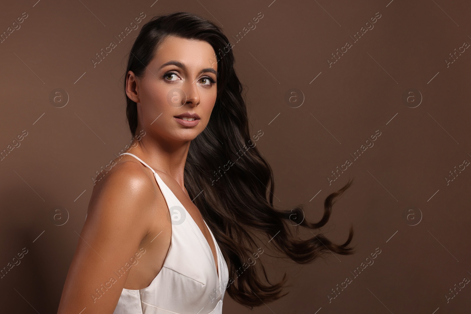 Photo of Hair styling. Beautiful woman with wavy long hair on brown background, space for text